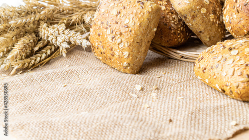 Delicious bread. Fresh loaf of rustic traditional bread with wheat grain ear or spike plant on linen texture background. Rye bakery with crusty loaves and crumbs. Homemade baking.