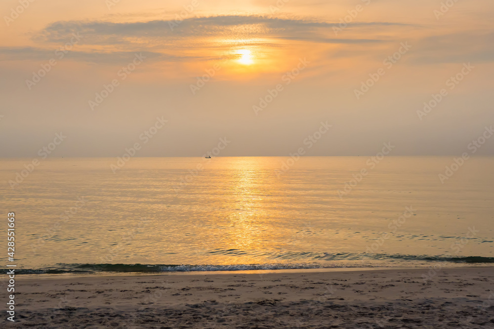 Beautiful golden orange sunrise over the ocean. The sunrise turning the sky yellow, orange reflects in the ocean.