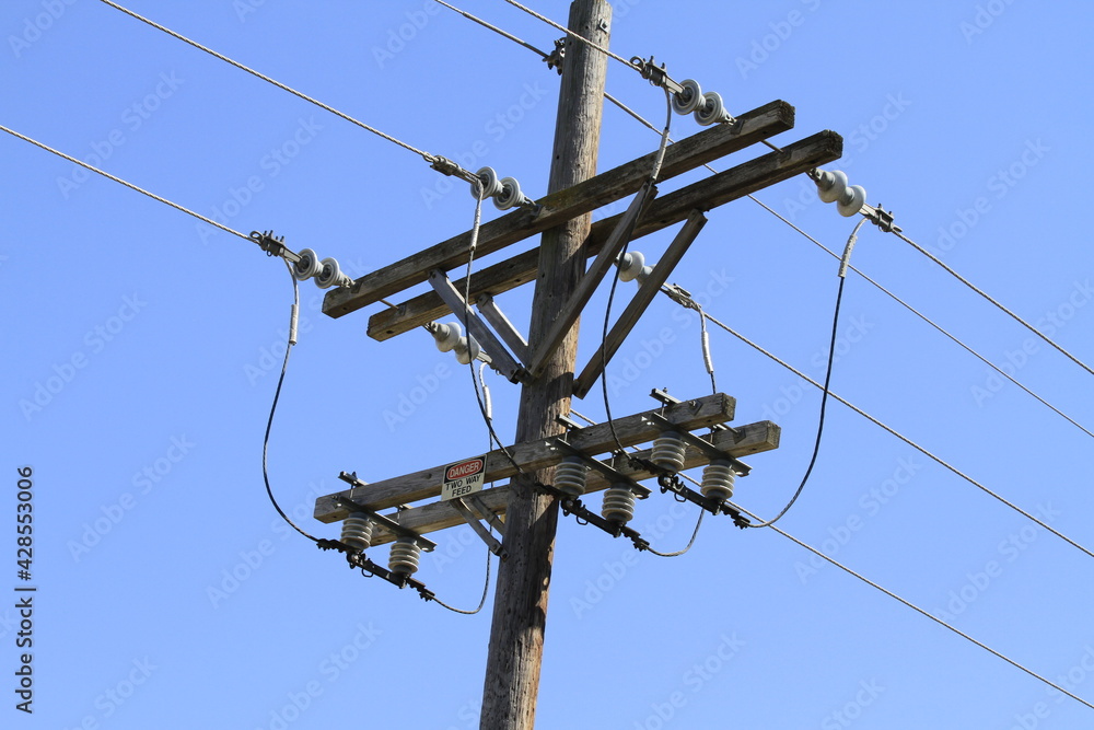 power lines and wires with pylons on a pole in Lyons Kansas USA with a blue sky. power lines and wires with pylons on a pole in Lyons Kansas USA with a blue sky.
