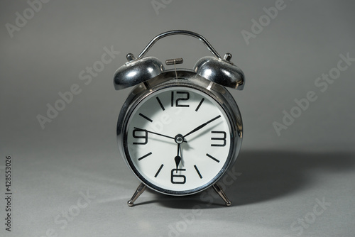 Old silver metal alarm clock on the solid grey background. photo