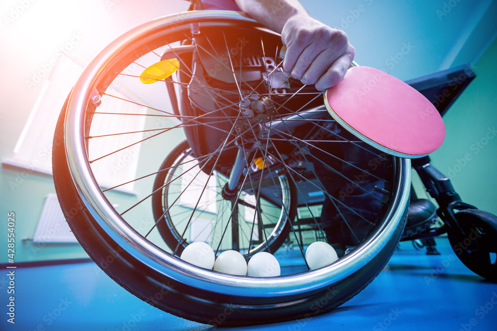 Disabled man in a wheelchair play at table tennis. Tennis balls fixed in a wheel
