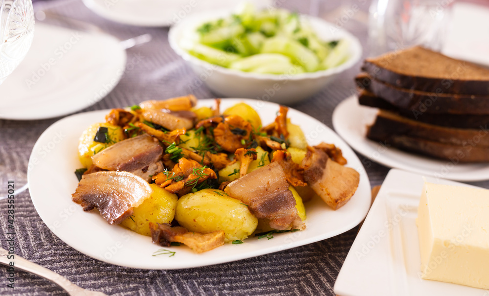 traditional rustic dish. fried potatoes with chanterelle mushrooms and pork brisket with herbs traditional rustic dish. fried potatoes with chanterelle mushrooms and pork brisket with herbs