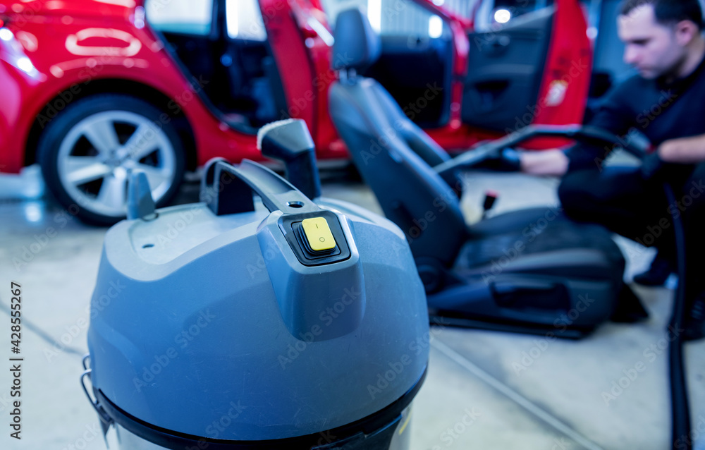 Car service worker cleaning car seat with vacuum cleaner. Car service worker cleaning car seat with vacuum cleaner.