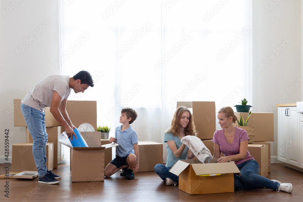 Caucasian family pick up waste items and clothes and put them in a paper box to donate and reuse or recycle. Parents and children pick up item in boxes for moving into the new home Caucasian family pick up waste items and clothes and put them in a paper box to donate and reuse or recycle. Parents and children pick up item in boxes for moving into the new home