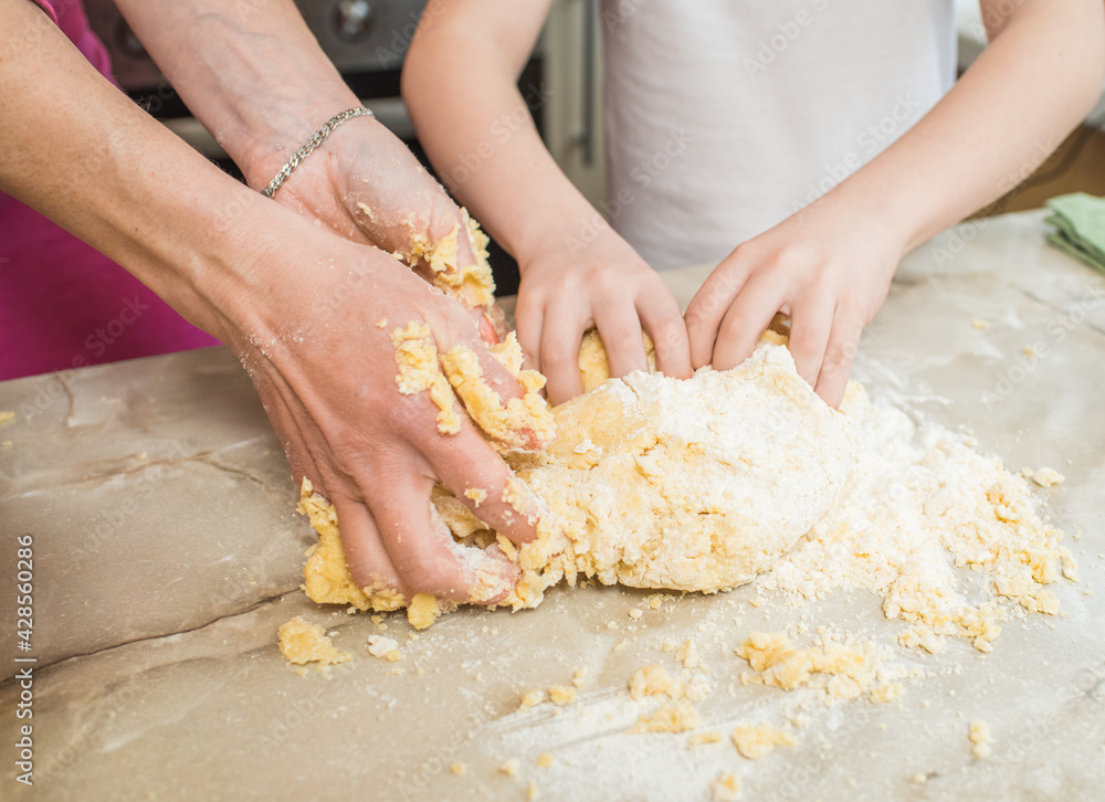 Hands of mother and son kneading dough together. Cooking at home