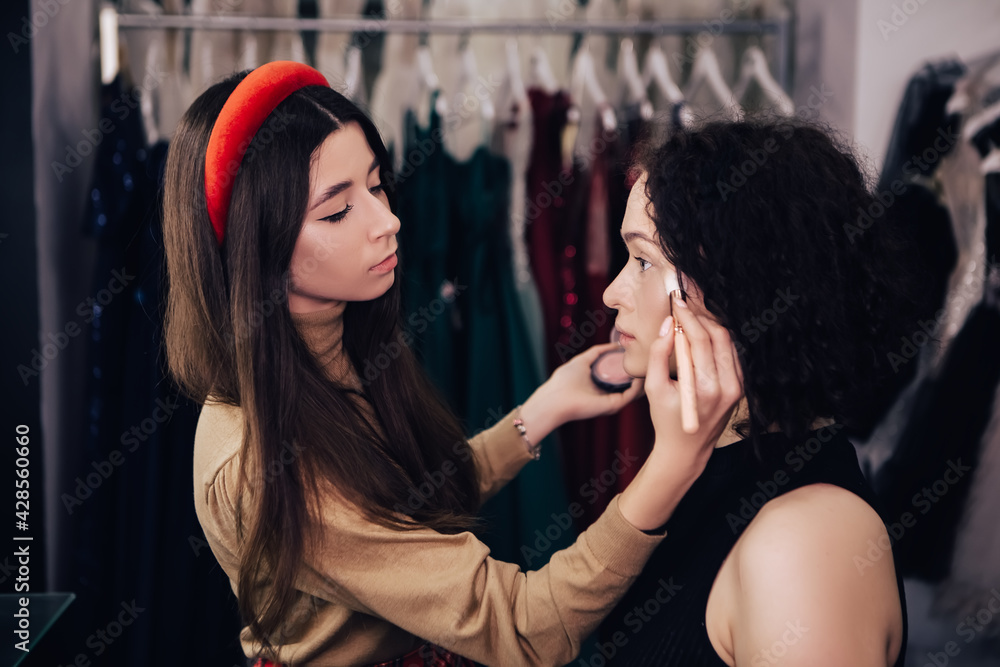 Make up talanted artist doing maquillage to woman applying powder. Visagist using brushes shadows facial professional cosmetics for makeup. Beauty industry studio, image with copy space.