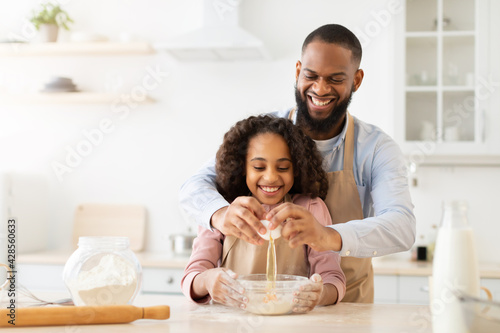 Happy black man and his child daughter preparing dough