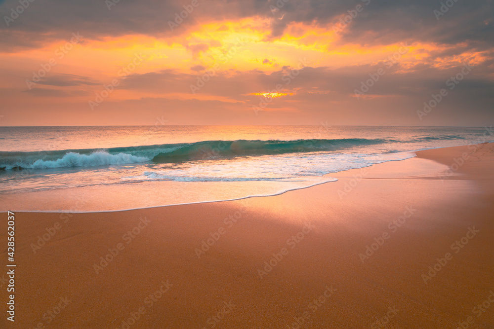 Foamy waves on sandy ocean beach under a beautiful sunset sky with clouds on Sri Lanka island.