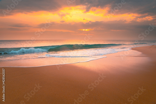 Foamy waves on sandy ocean beach under a beautiful sunset sky with clouds on Sri Lanka island. © stone36
