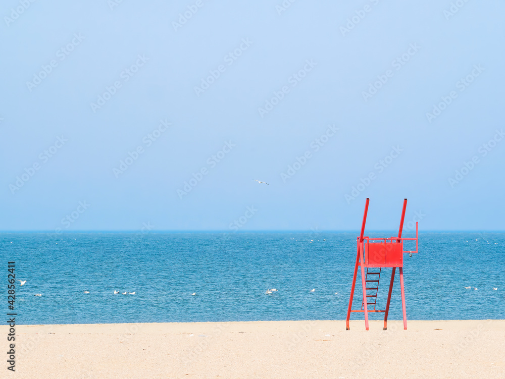 Red lifeguard chair on an empty beach.