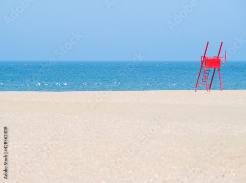 Red lifeguard chair on an empty beach.