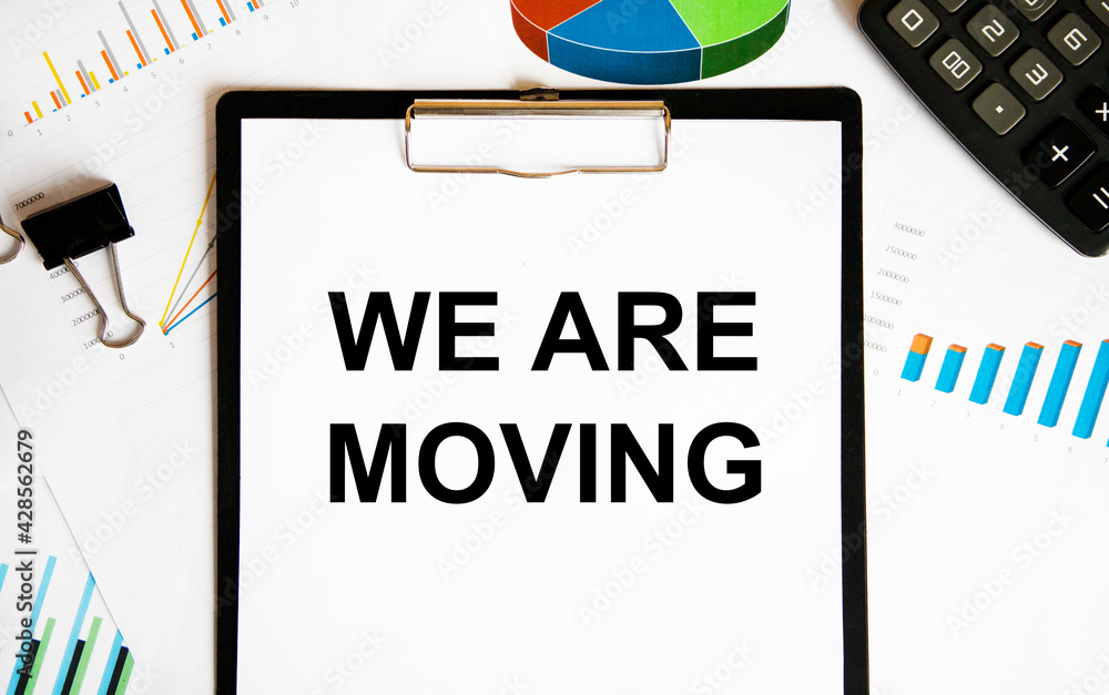 On the letter tablet is the text we ARE MOVING, a number of graphs and diagrams, a calculator and clips for paper. On the letter tablet is the text we ARE MOVING, a number of graphs and diagrams, a calculator and clips for paper.