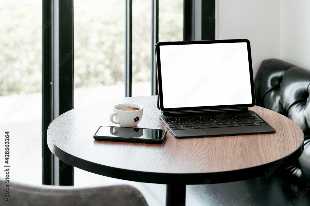 Fototapeta premium Blank screen tablet with keyboard on round coffee table.