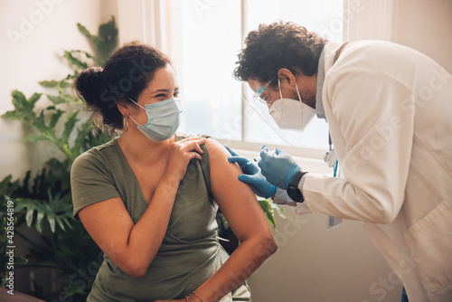 Fotografi Frontline worker vaccinating woman at her home
