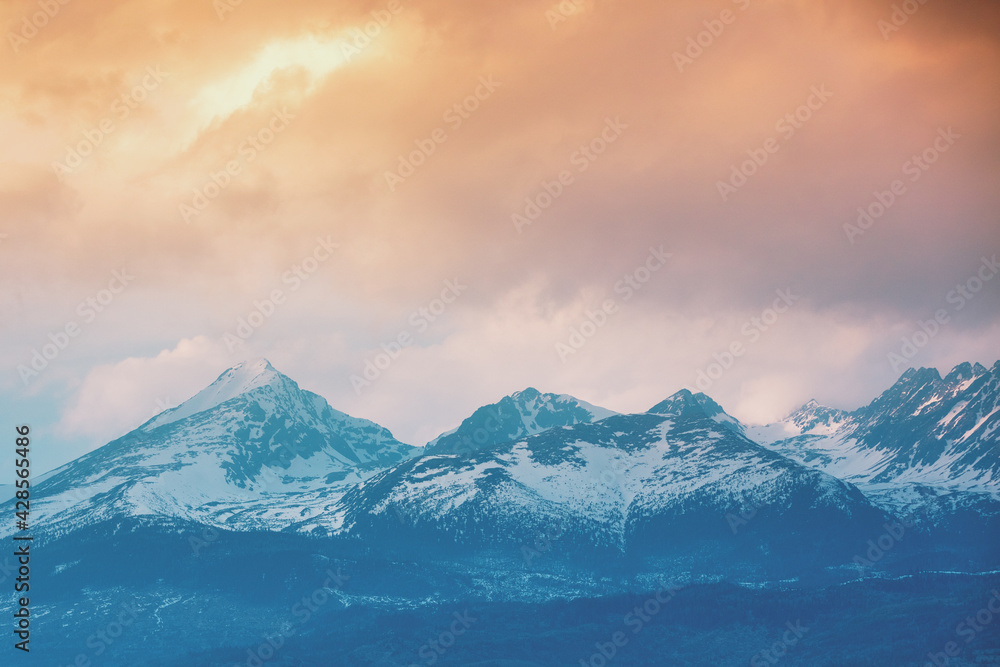 Beautiful snow-capped mountains against the backdrop of a sunset sky with dramatic clouds. Liptovsky Sea Region, High Tatras, Slovak Republic, Europe