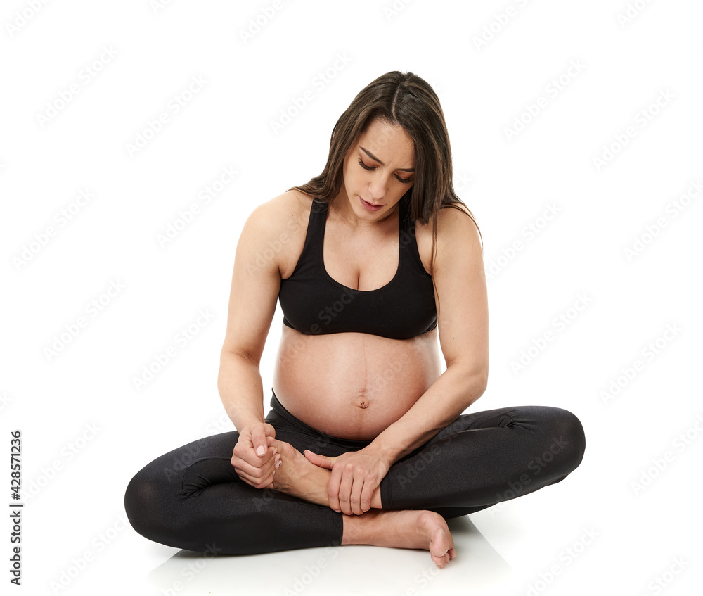 Pregnant woman massaging her ankles Pregnant woman massaging her ankles