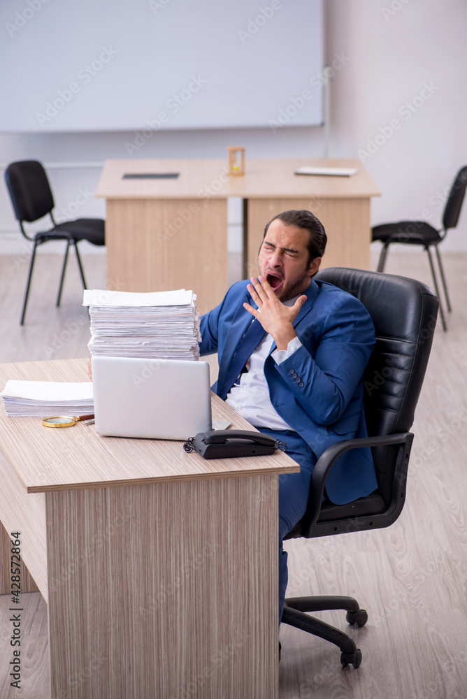 Young male employee and too much work in the office Young male employee and too much work in the office