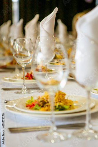 Close-up of a banquet set table: wine / champagne glasses, napkins and salad. For a solemn holiday