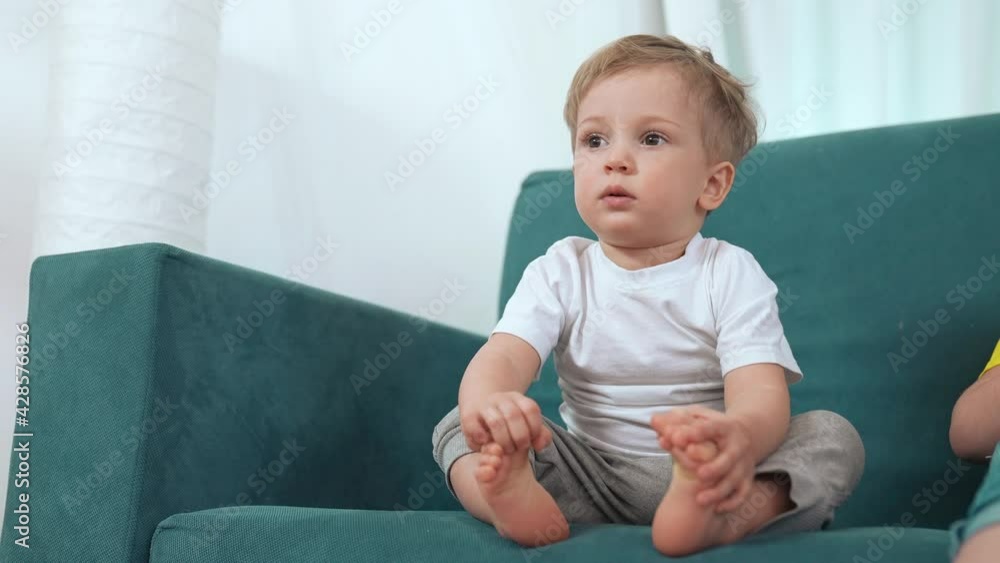 Boy baby home. little kid son a newborn sitting on the couch portrait at home. concept happy family stay home. baby blond portrait face. happy family son sitting on the couch resting at home fun Boy baby home. little kid son a newborn sitting on the couch portrait at home. concept happy family stay home. baby blond portrait face. happy family son sitting on the couch resting at home fun