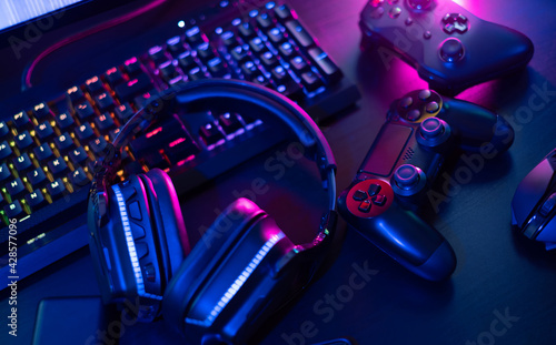 gamer work space concept, top view a gaming gear, mouse, keyboard, joystick, headset with rgb color on black table background. photo