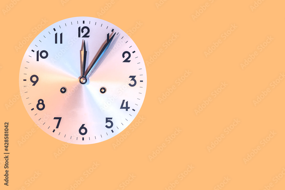 circular mechanical clock dial that marks five minutes past twelve,isolated on orange color background with copy space circular mechanical clock dial that marks five minutes past twelve,isolated on orange color background with copy space
