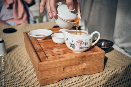 Hands of man brewing puerh tea. Man pours tea from gaiwan to bowl at tea tray. Chinese traditional gongfu cha tea ceremony. photo
