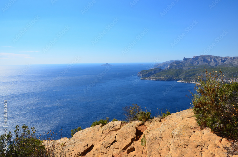 Stunning view from the cliff Cap Canaille towards the bay of the town Cassis in South France, reflections of sunlight on blue mediterranean sea
