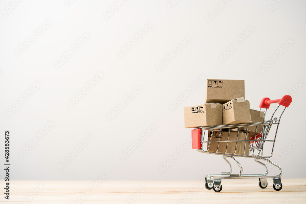 Shipping paper boxes inside Red shopping cart trolley on table with copy space , shopping and commerce concept.