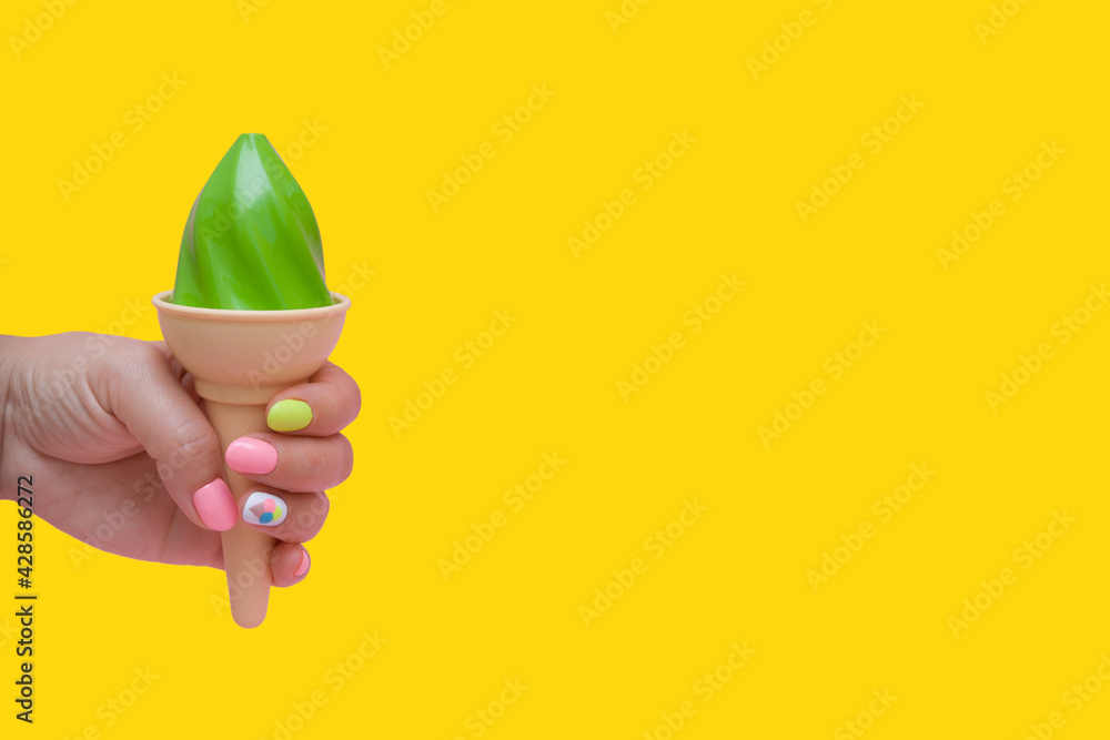 Female hand with summer manicure and toy ice cream on bright background with copy space Female hand with summer manicure and toy ice cream on bright background with copy space