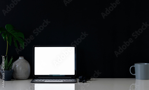 Mockup blank screen tablet with decoration on white table and black background, creative workspace in dark color.