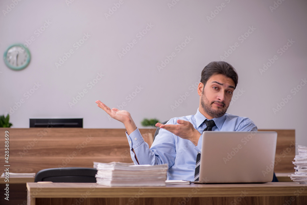 Young male employee and too much work in the office Young male employee and too much work in the office