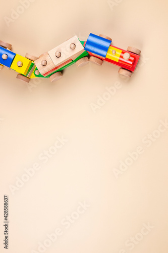 Wooden toy train with multi colored blocks on pastel beige background. Top view