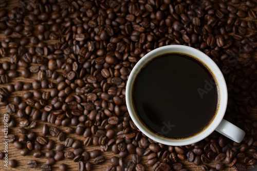 Black coffee and coffee beans roasted on wooden background,Top view,copy space.