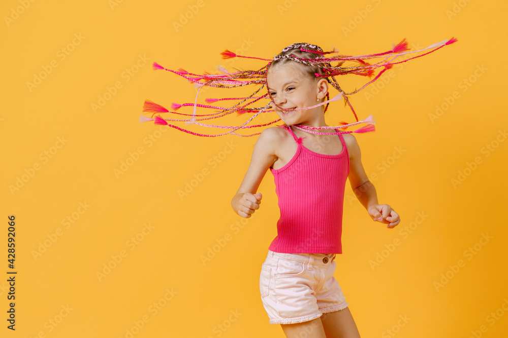 Stylish girl with pink dreadlocks and posing on a yellow backgro Stylish girl with pink dreadlocks and posing on a yellow backgro
