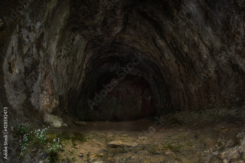 View into the entrance of a dark, tunnel-like cave in the Plitvitzer National Park.