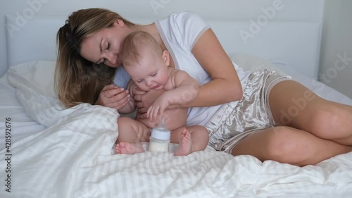 A young mother rocks the baby in her arms. The baby cries and does not want to sleep. photo