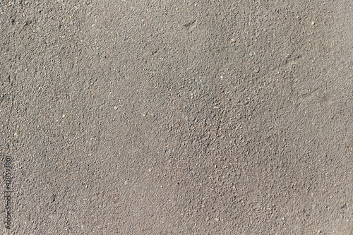 Grey asphalt with scratches and damages sunny day Background