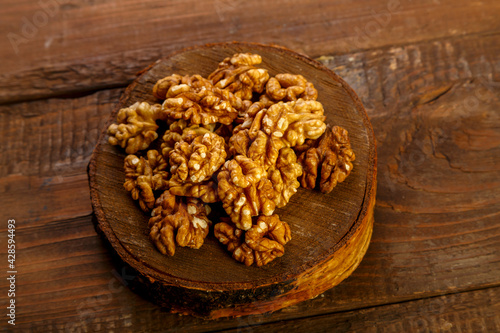Walnuts are scattered on a round board on a wooden table.