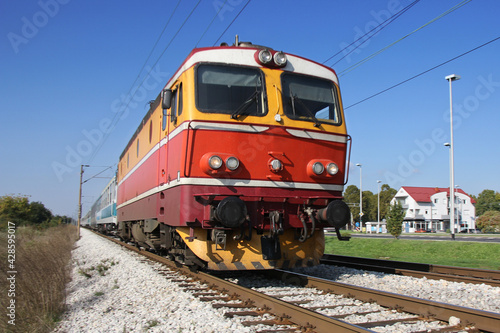 Red passenger train passing railroad on a sunny day