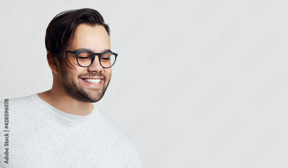 Portrait of young smiling man with glasses on white background with copy space.