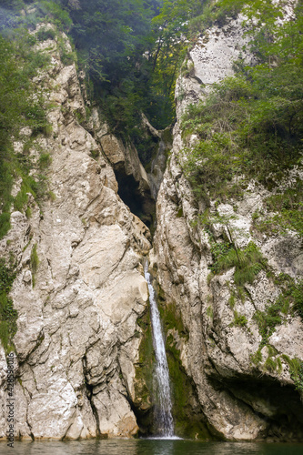 Waterfall in a crevice between the rocks behind the trees. Agur waterfalls 