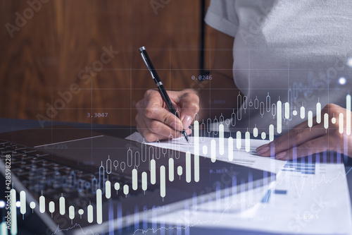 A client in casual wear is signing the contract to invest money in stock market. Internet trading and wealth management. Forex and financial hologram chart over the desk. Women in business concept.