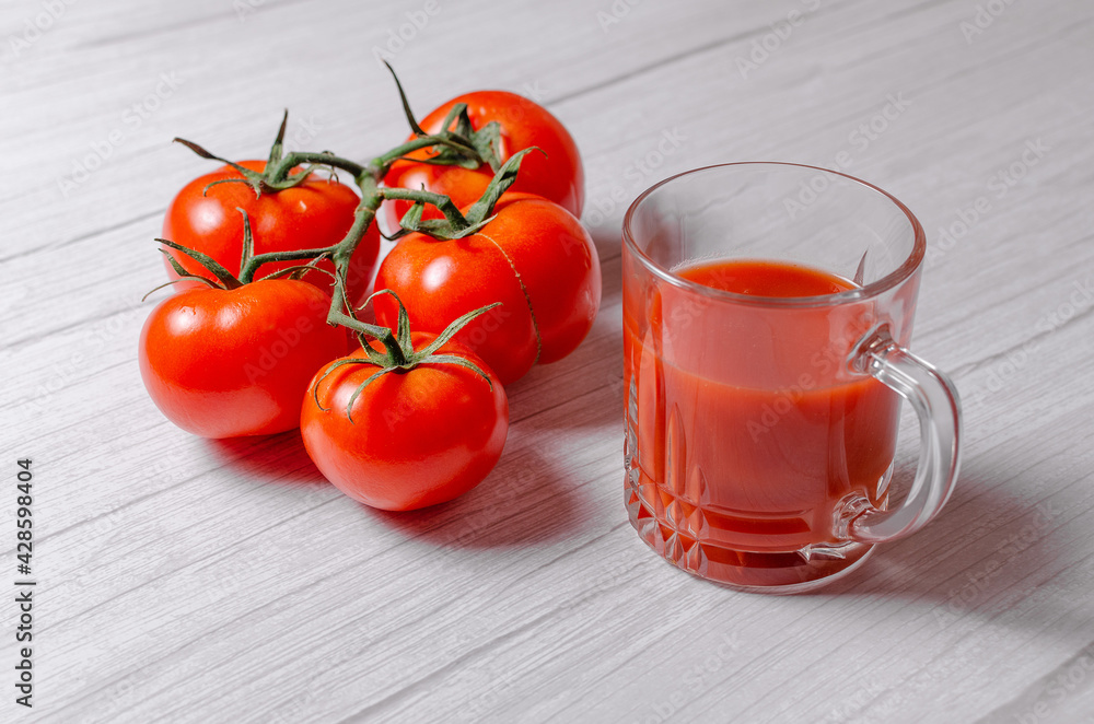 Fresh tomatoes, isolated on white with a glass of fresh tomato juice Fresh tomatoes, isolated on white with a glass of fresh tomato juice