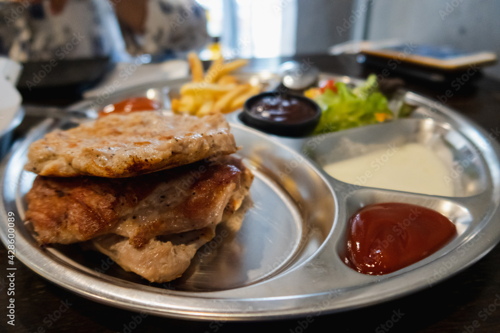 Pork steak with fries and vegetables on the food tray Pork steak with fries and vegetables on the food tray
