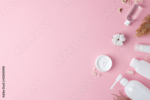 Cosmetic background with skin care products on pink. Flat lay, copy space