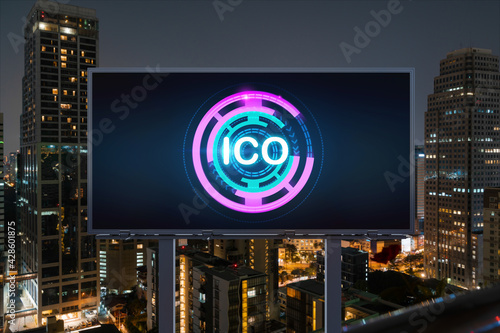 ICO hologram icon on billboard over panorama city view of Bangkok at night time. The hub of blockchain projects in Southeast Asia. The concept of initial coin offering, decentralized finance