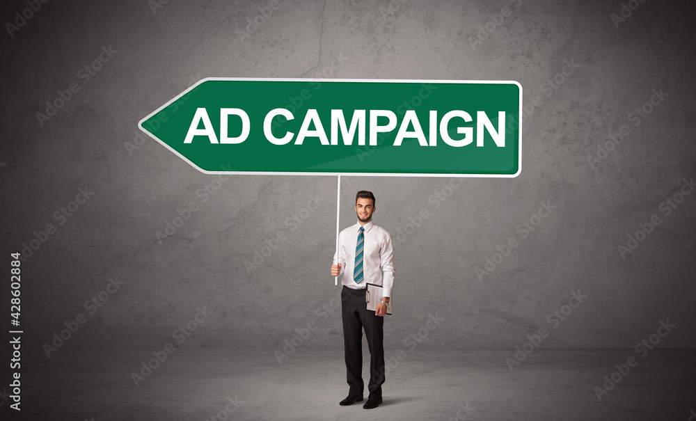 Young business person in casual holding road sign Young business person in casual holding road sign