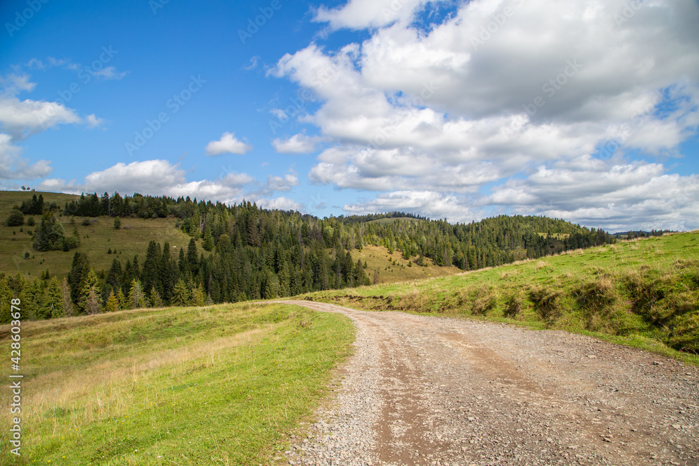 road on a background of forest and hills and fields blue sky with clouds. Landscape nature.