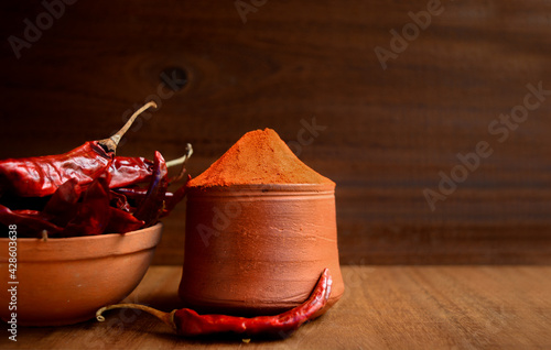 Red chilli raw and powder kept on wooden table