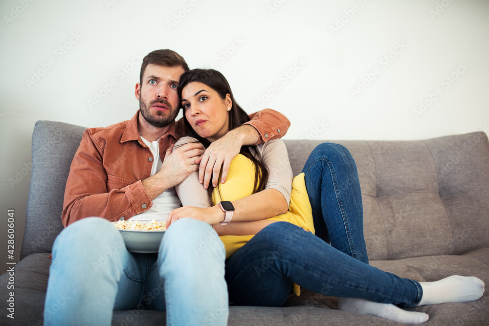 Man and woman watching horror movie at home